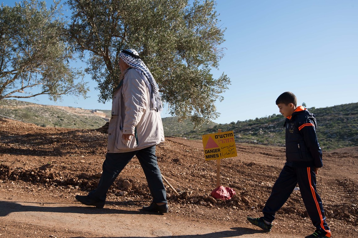 Kayyed and Karam walk along a path next to the former minefield, HALO Trust.