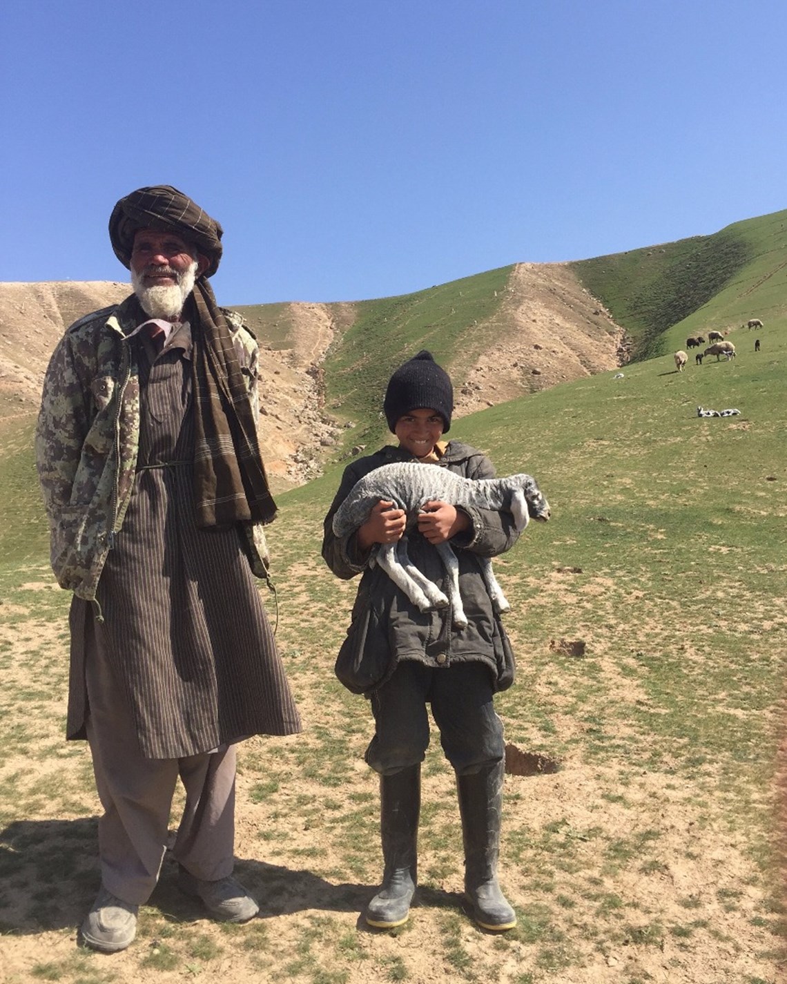 Abdul Hakim stands with his grandson on the land HALO cleared of mines