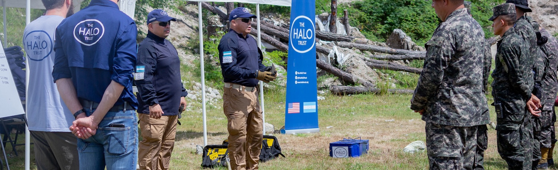 Explosive ordnance disposal trainers speak to military personnel and HALO staff outside