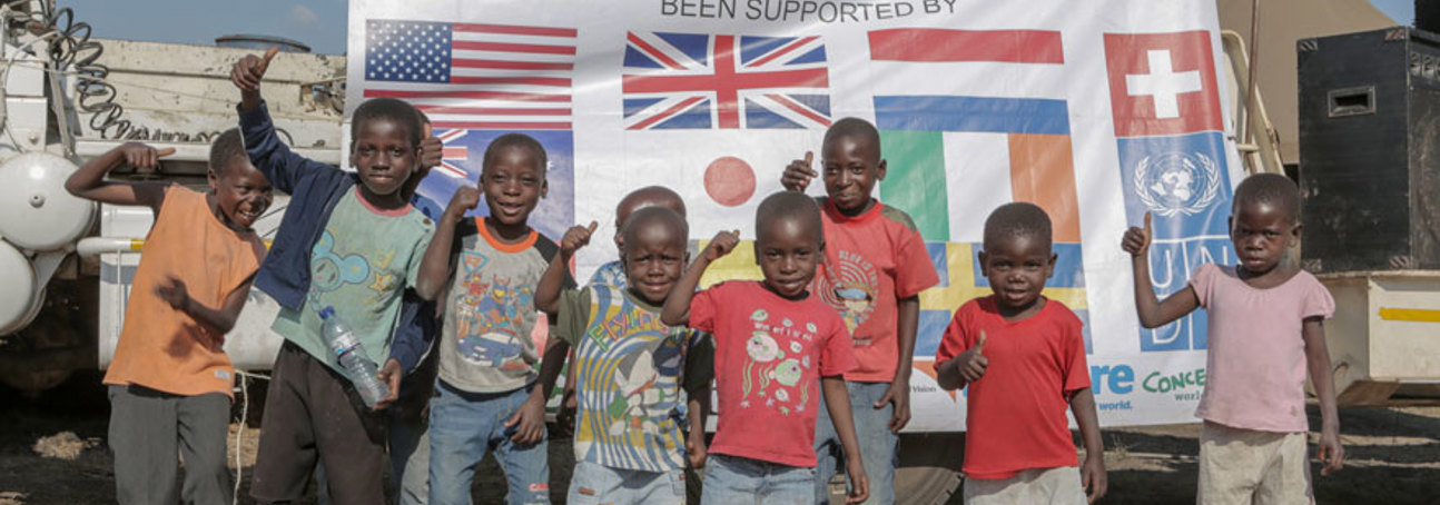 Children smile in front of a sign celebrating Mozambique's mine-free status