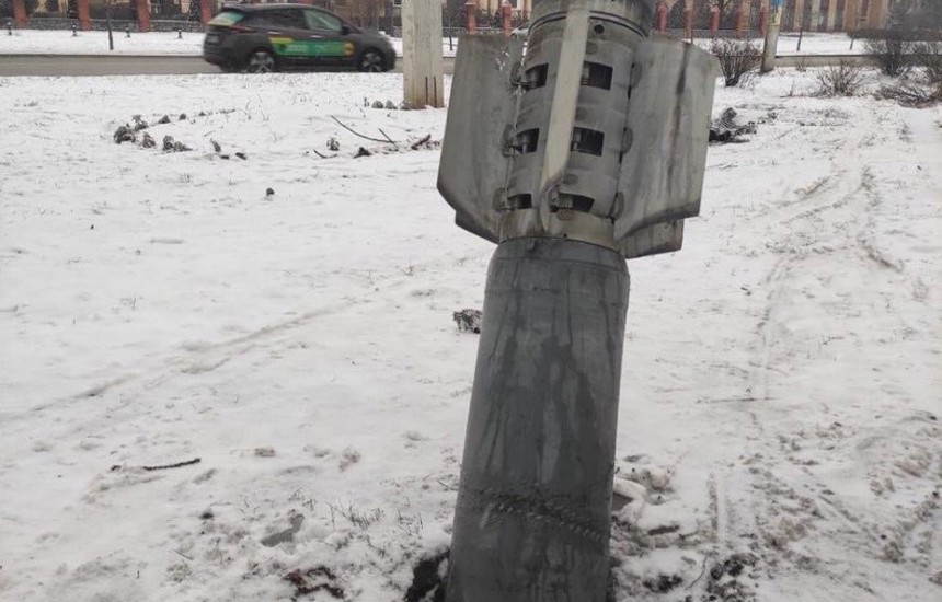 A bomb sticking out of the ground next to a snow covered street in Ukraine