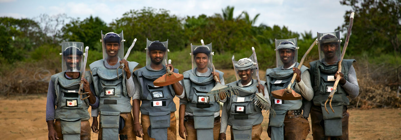 A team of Japan-funded deminers stand holding their tools in Sri Lanka