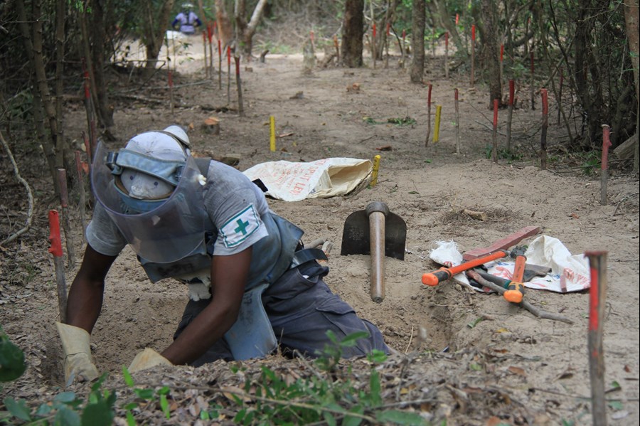 A deminer conducts manual excavation at BND11e.The yellow sticks in the background mark where a number of mines have been found and removed