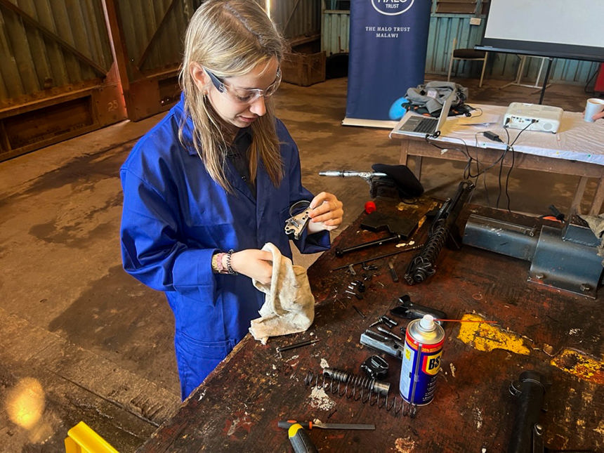 Maria wears overalls and goggles during an armourer's course in Malawi