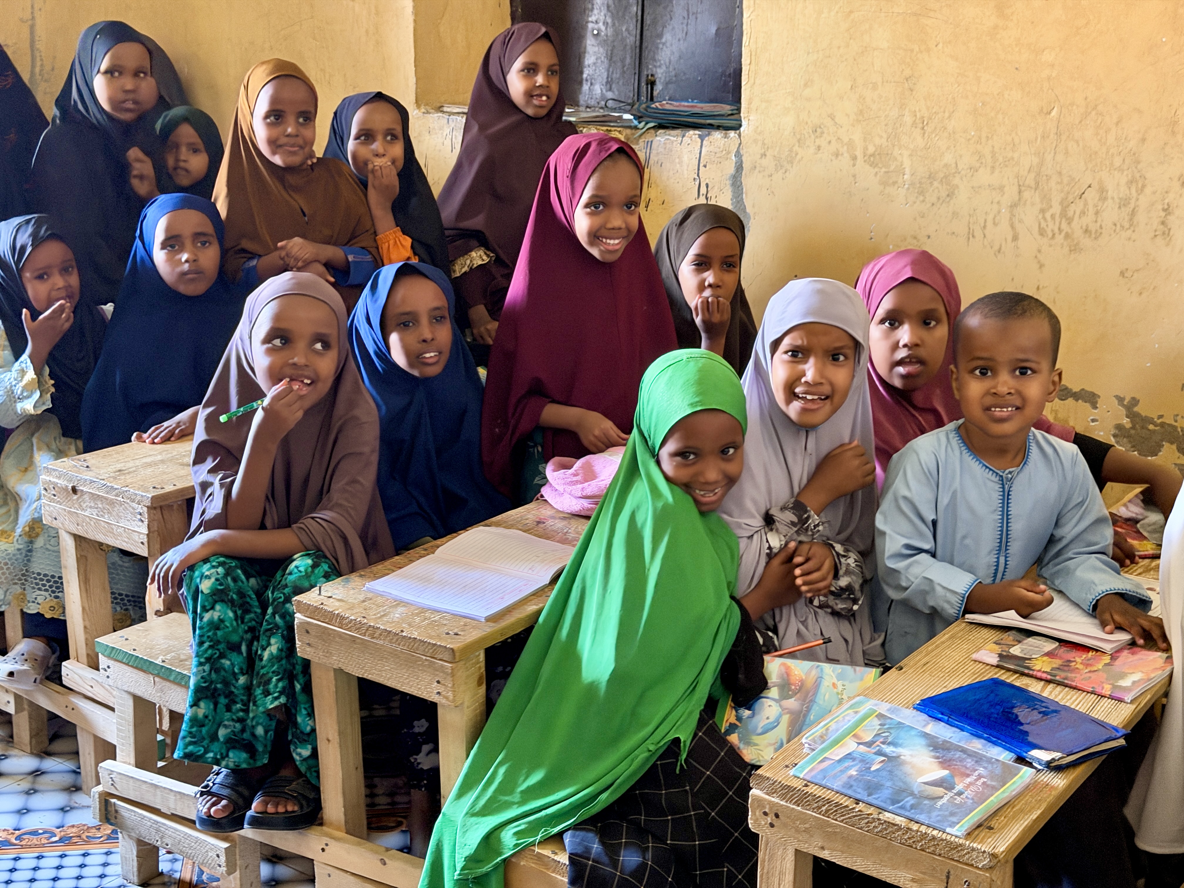 a group of young schoolchildren shyly giggle at the camera as they learn about safety in a classroom in Somalia