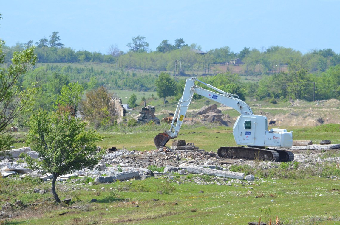 Japanese-funded armoured excavator Hitachi ZX130 conducts mechanical clearance.