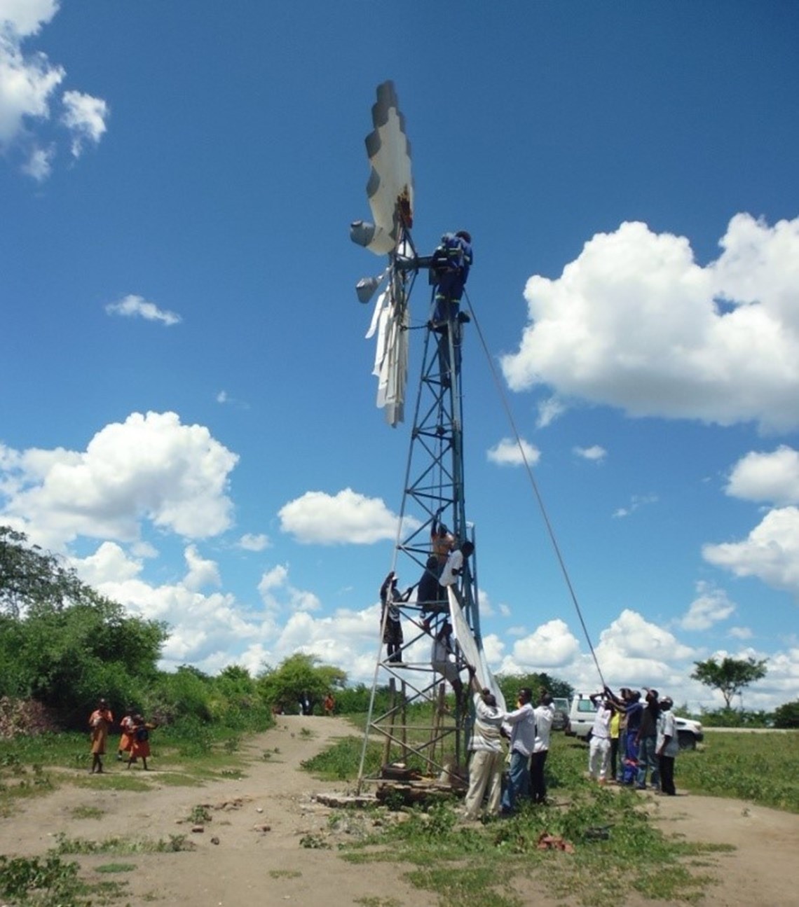 Children from the primary school (left) walk past the windmill as the local community begin to hoist the final part, HALO Trust.