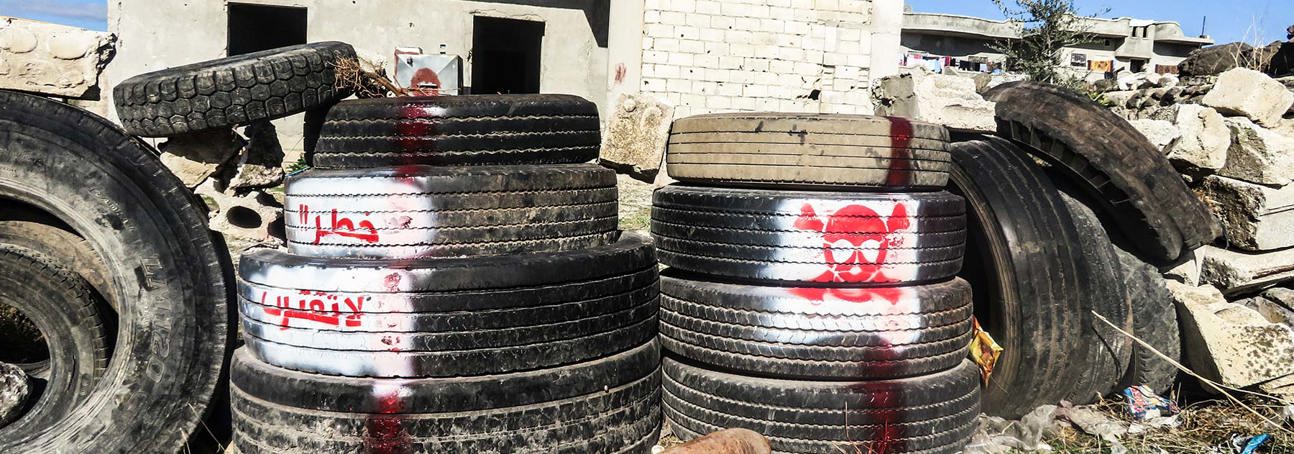 Spray-painted tyres and markings surrounding an unexploded rocket near a home in Syria