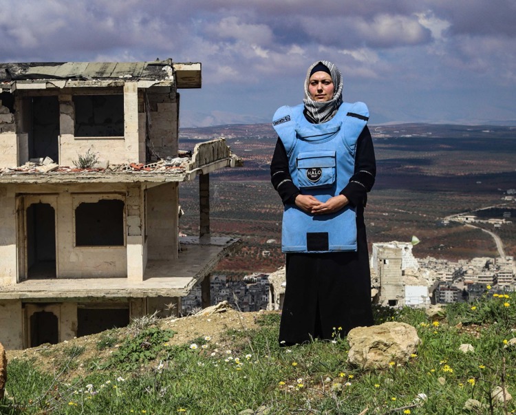 Lama Hajj wears PPE in front of a destroyed building in Syria