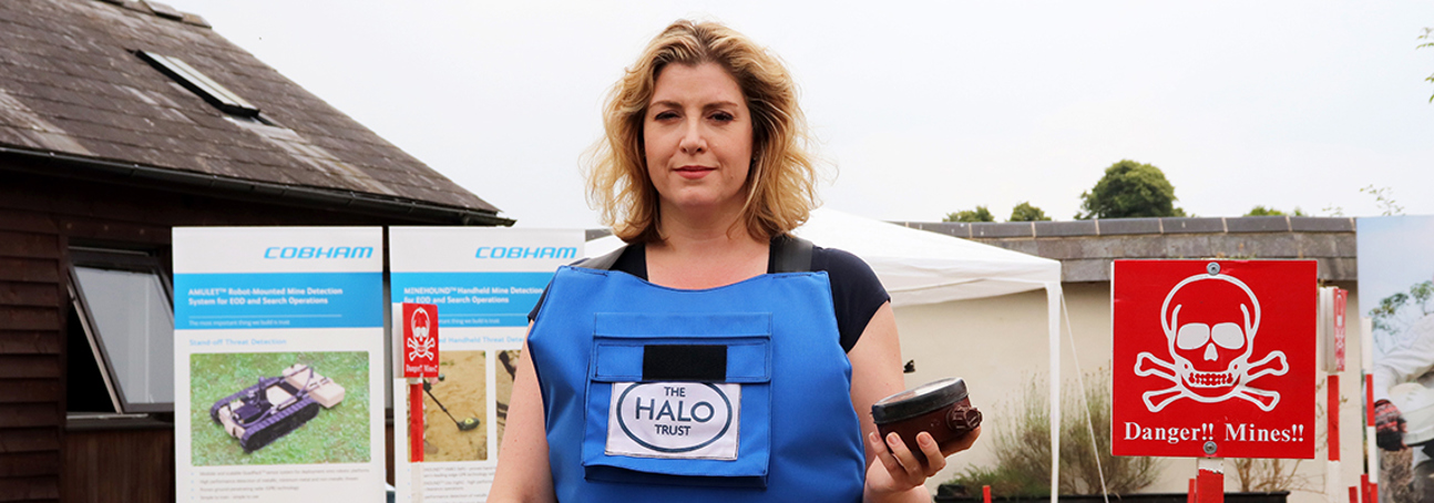 Former Secretary of State for International Development, Penny Mordaunt stands in PPE and holds a landmine during a visit to the HALO office