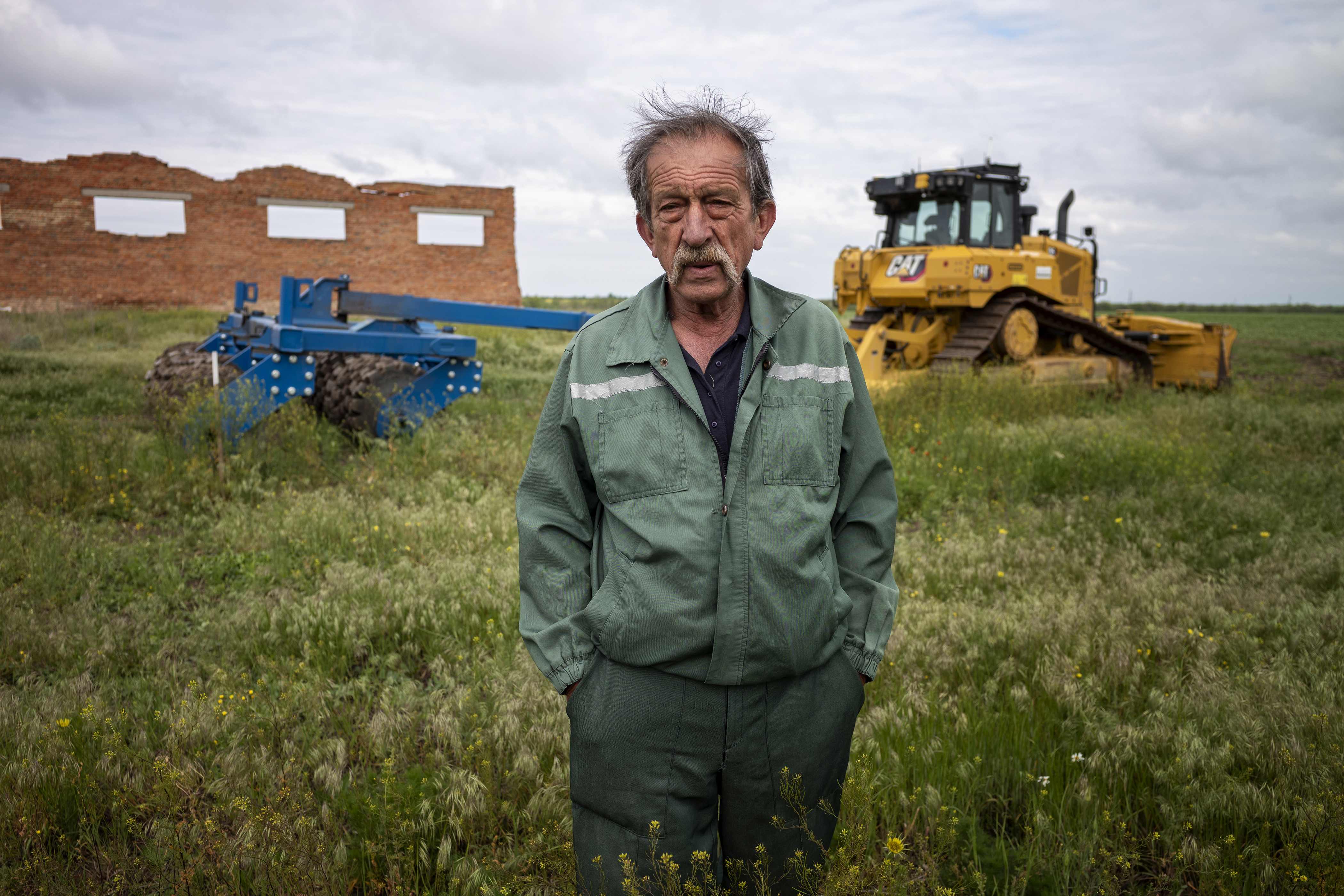 A man stands in a field with rollers behind him