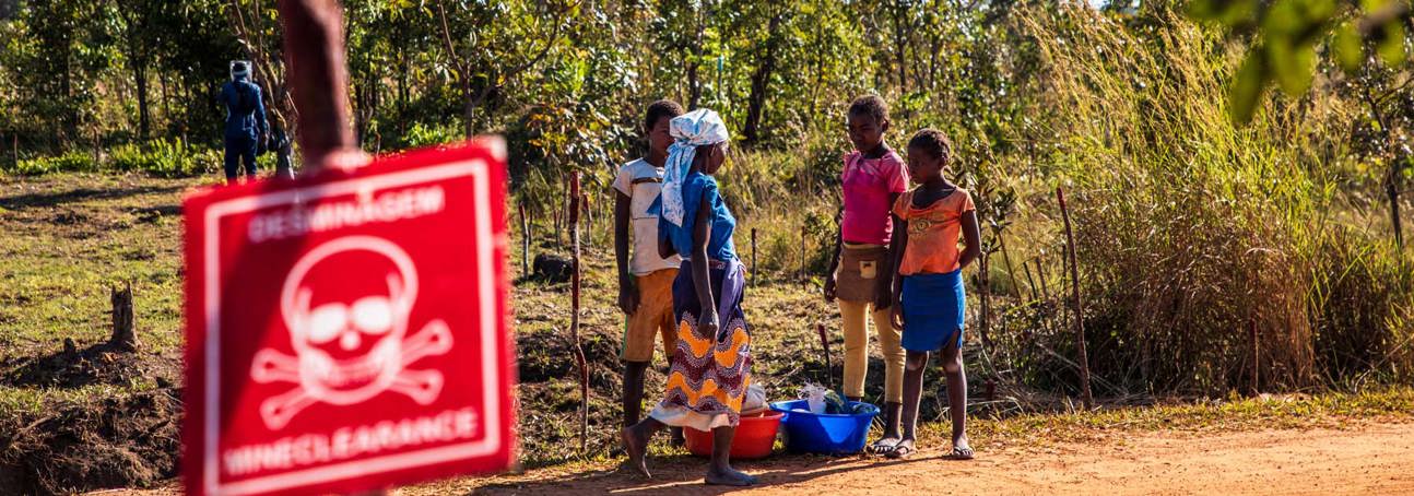 Four children stand on a road behind a danger mine sign in Angola