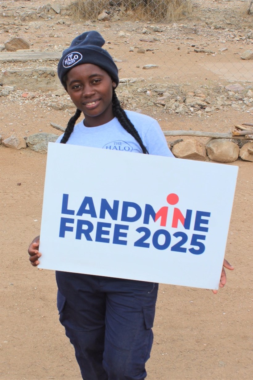 Deminer Teresa Nene from Angola holds sign showing her support for a Landmine Free 2025, image by The HALO Trust.