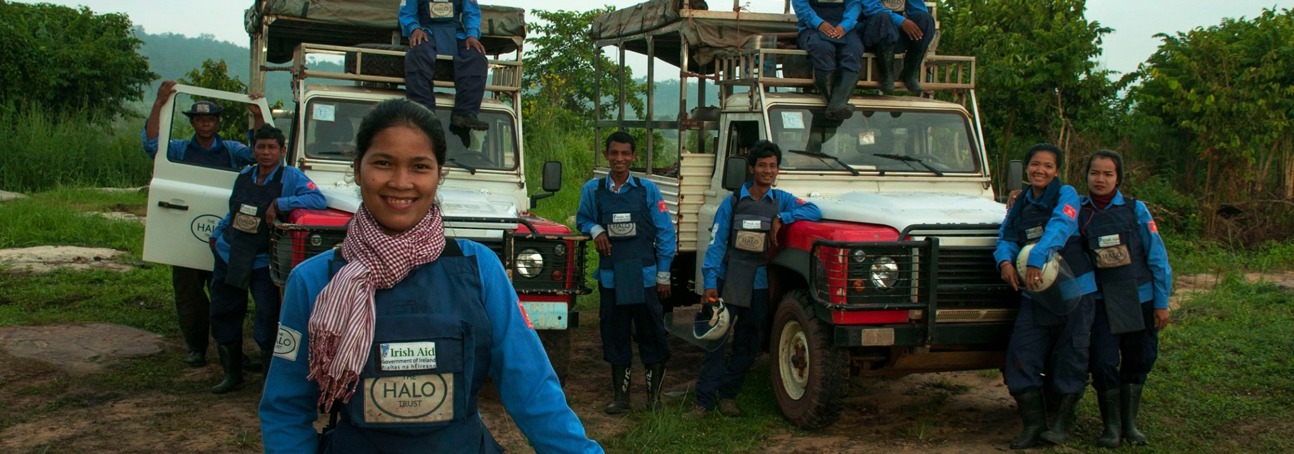 Deminers wearing protective gear pose with HALO vehicles 