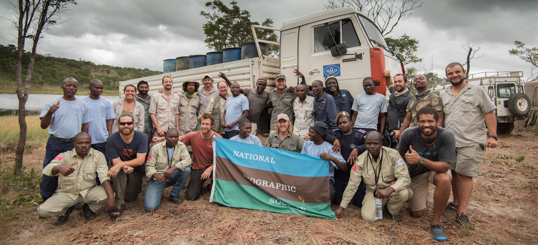 HALO and National Geographic Staff stand in front of HALO vehicles and hold the National Geographic flag