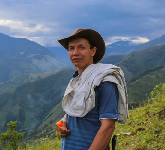 Man in rural Tolima, Colombia, standing against a backdrop of mountains.