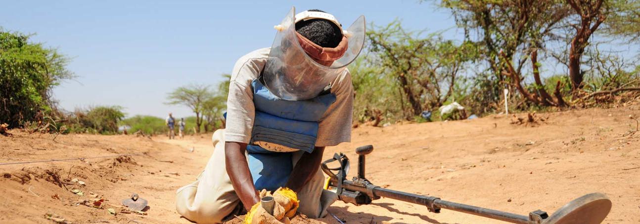 A deminer excavates a signal in PPE and a visor in Somalia