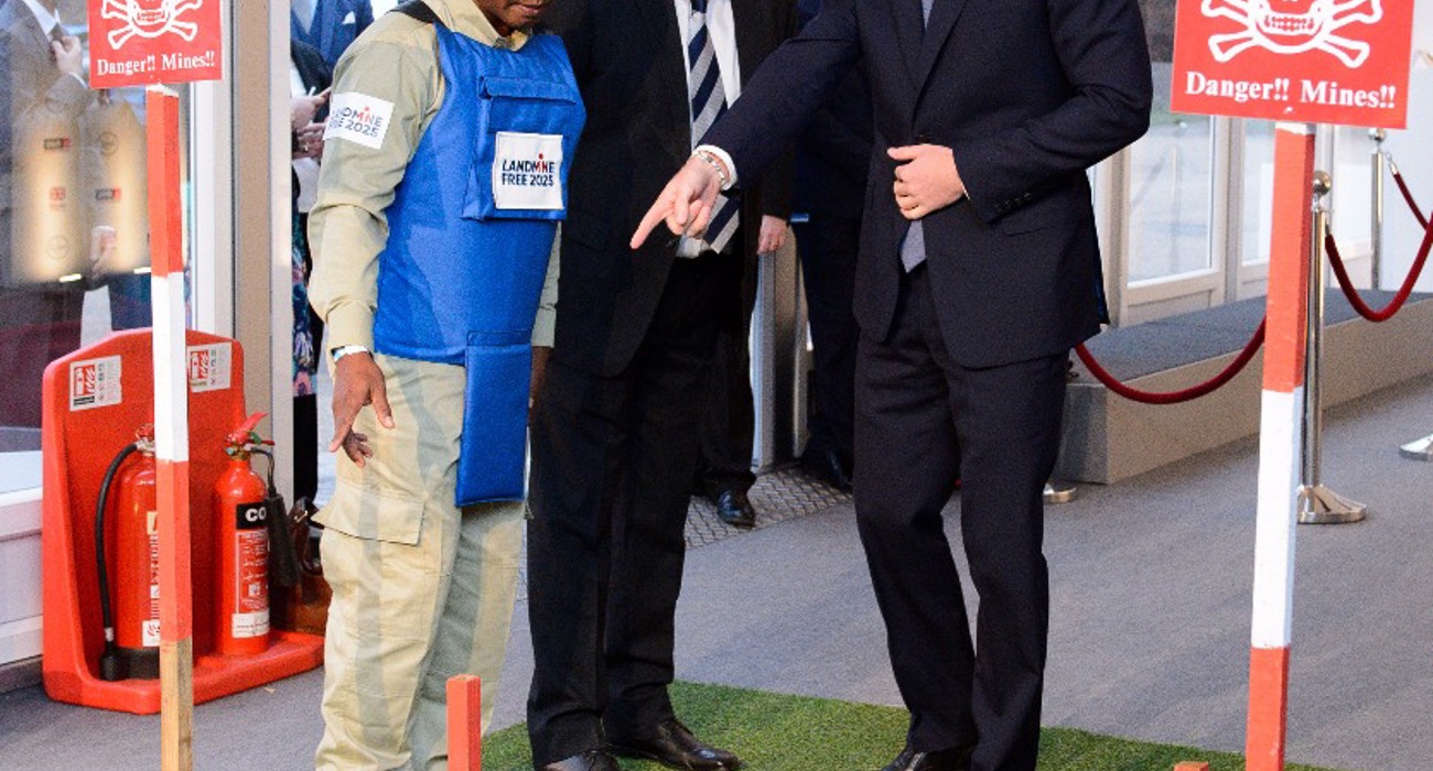 Prince Harry talks with a HALO Trust staff member wearing a protective vest near a display minefield at an event