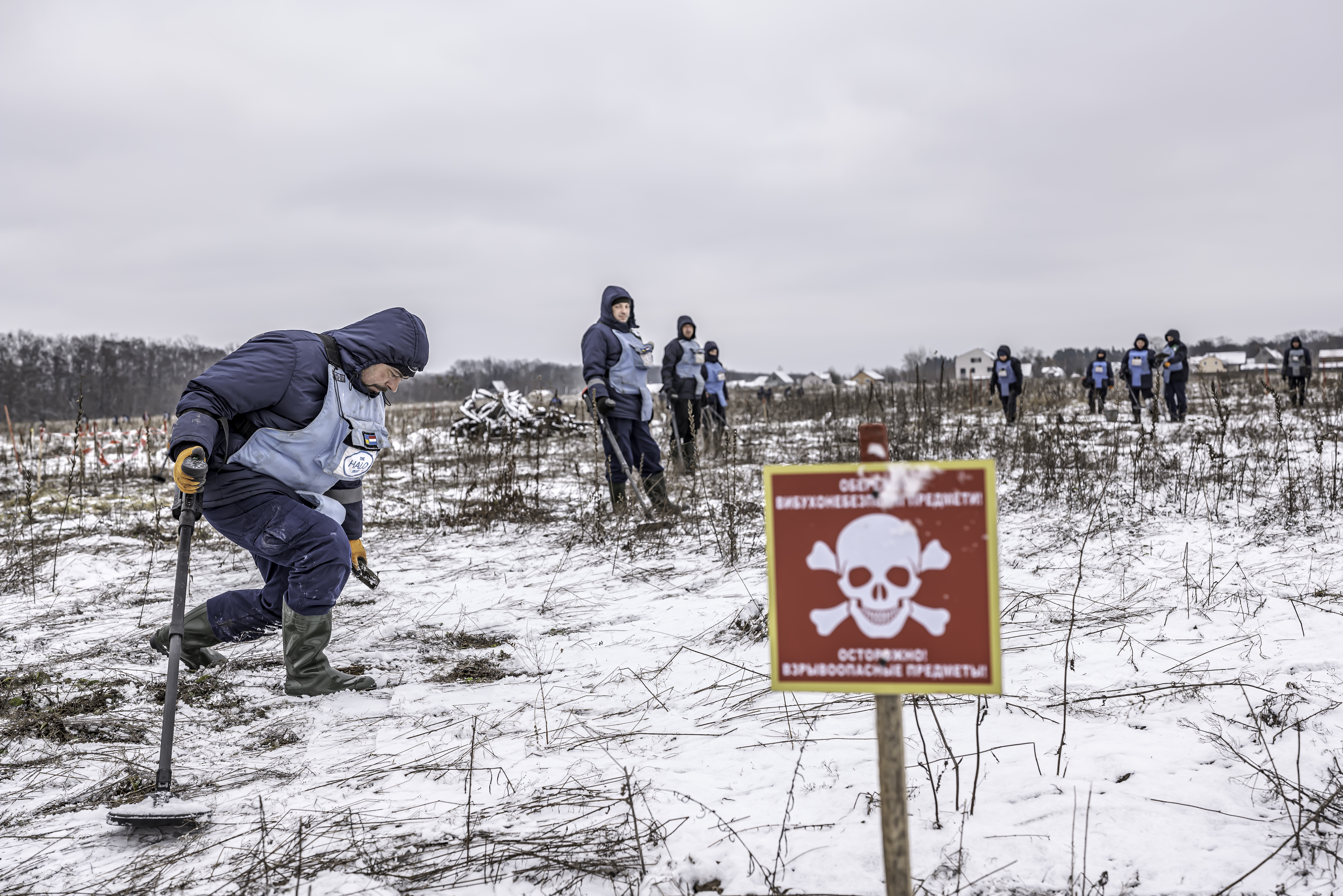 Deminers standing on a snowy minefield