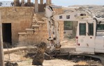 A armoured digger conducts clearance and removal of explosives from the contaminated Franciscan Compound