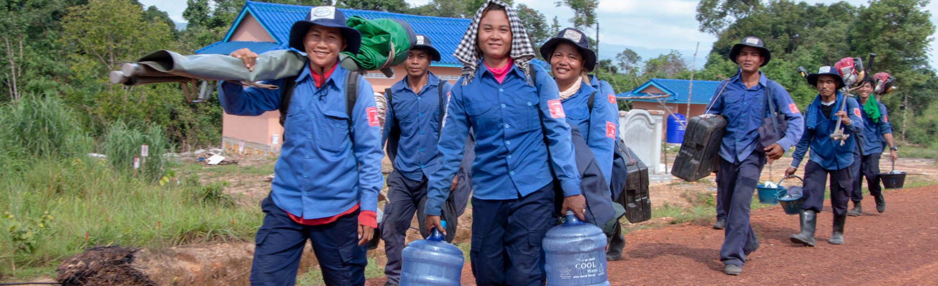 A HALO team carry equipment and water on a road in Cambodia