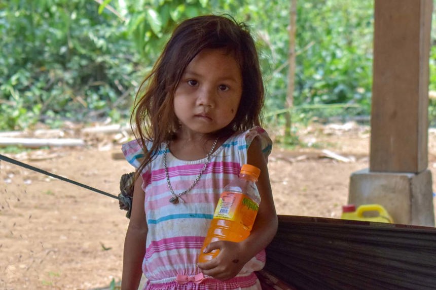 A little girl stands outside while holding a drink bottle