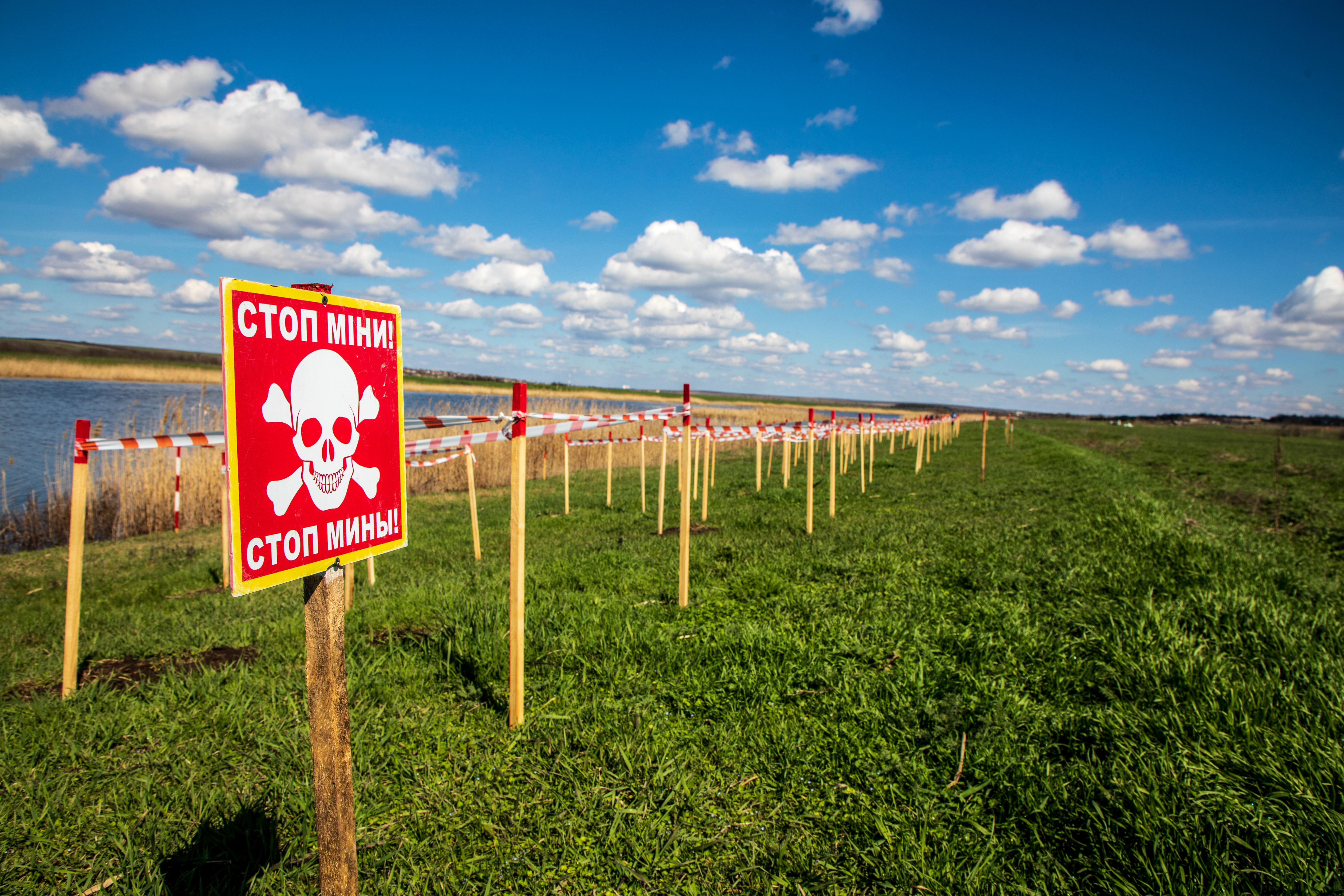 A minefield in Mykolaiv oblast is lined with mine stick markers and a mine warning sign