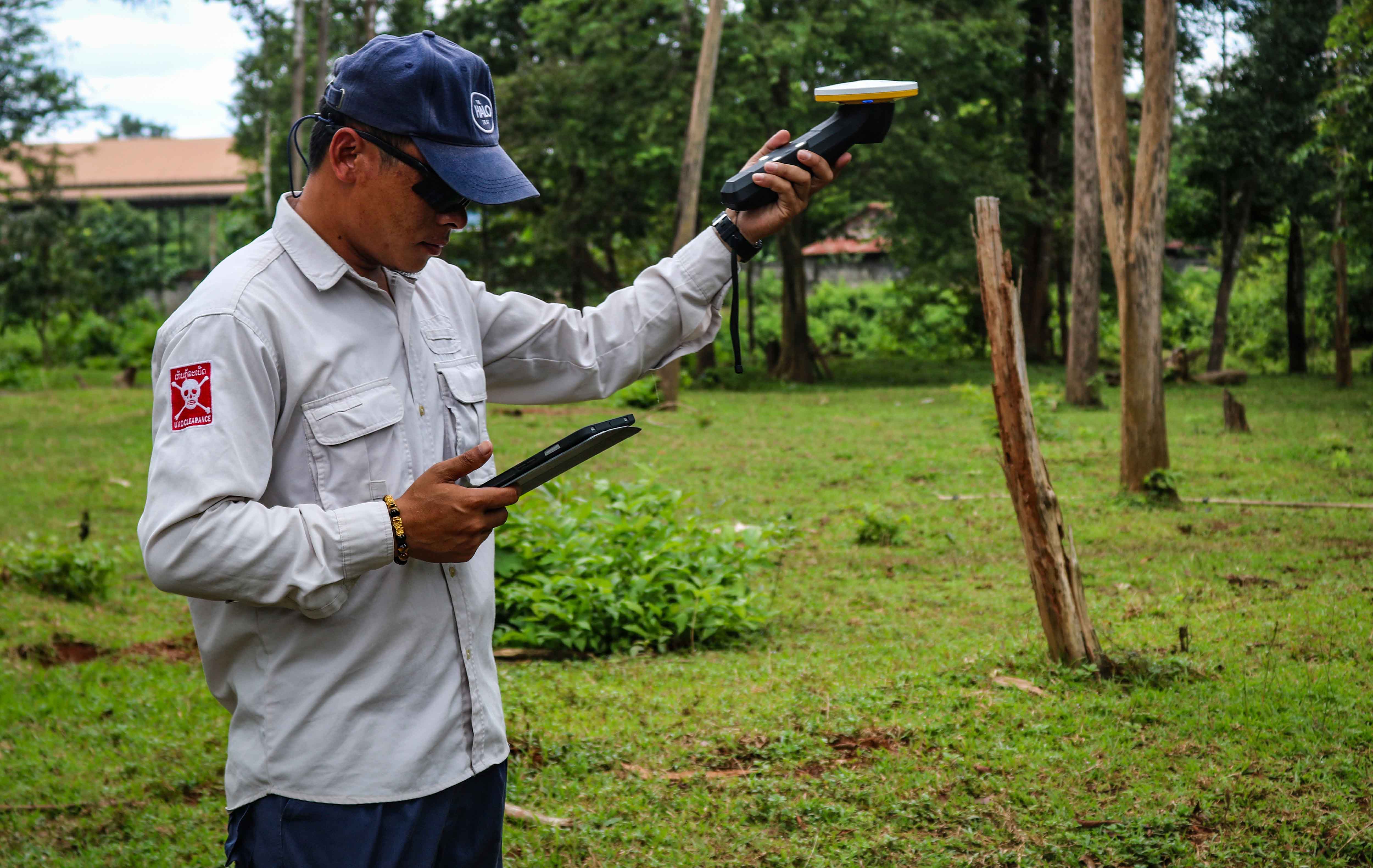 HALO Trust technician using a digital GPS unit to mark the edge of a crater caused by a bomb