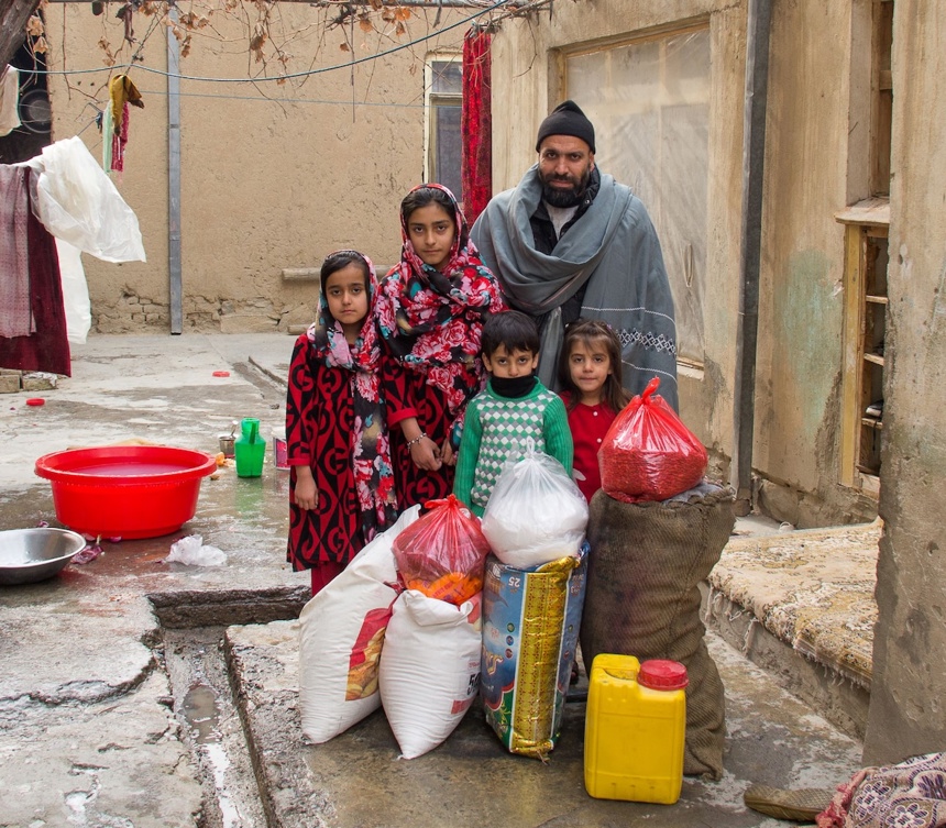 A family standing with bags of provisions at a food bank 