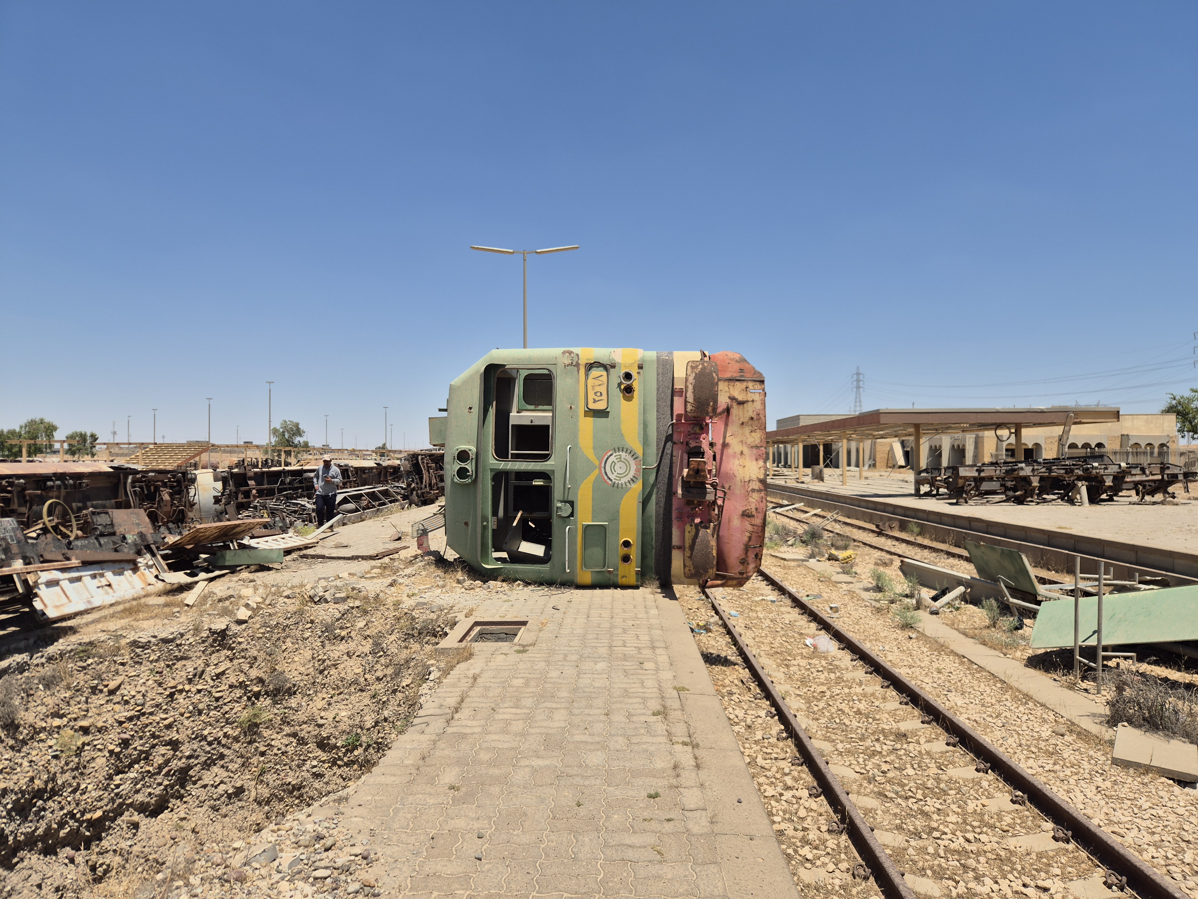 A green and yellow train on its side on the derelict Baiji railway track