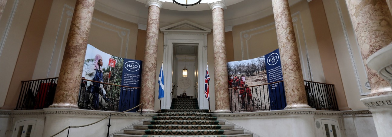 The staircase at Dover House, next to large banners featuring photos of HALO staff in the field