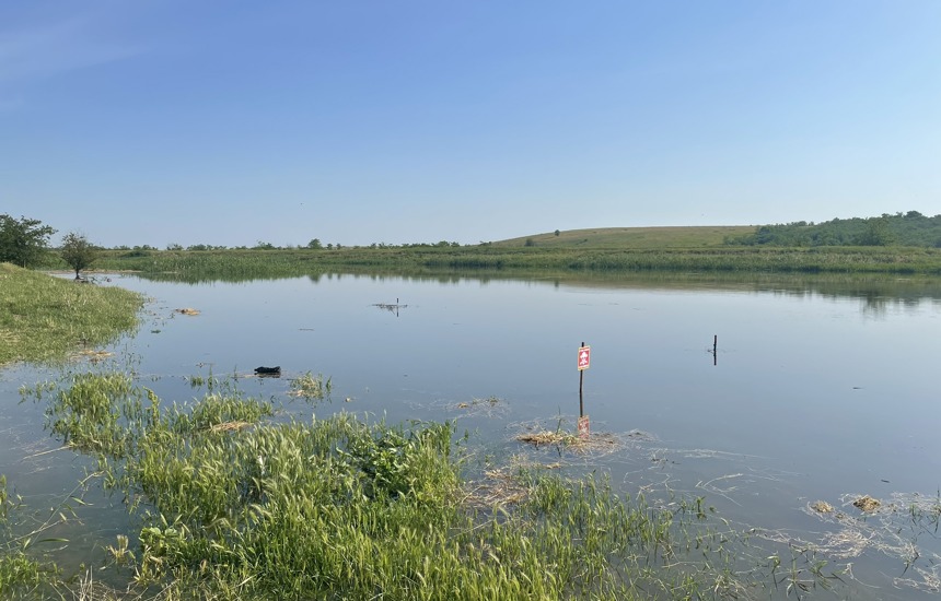 A danger mines sign depicts the hidden threat of contamination in a flooded field in Ukraine