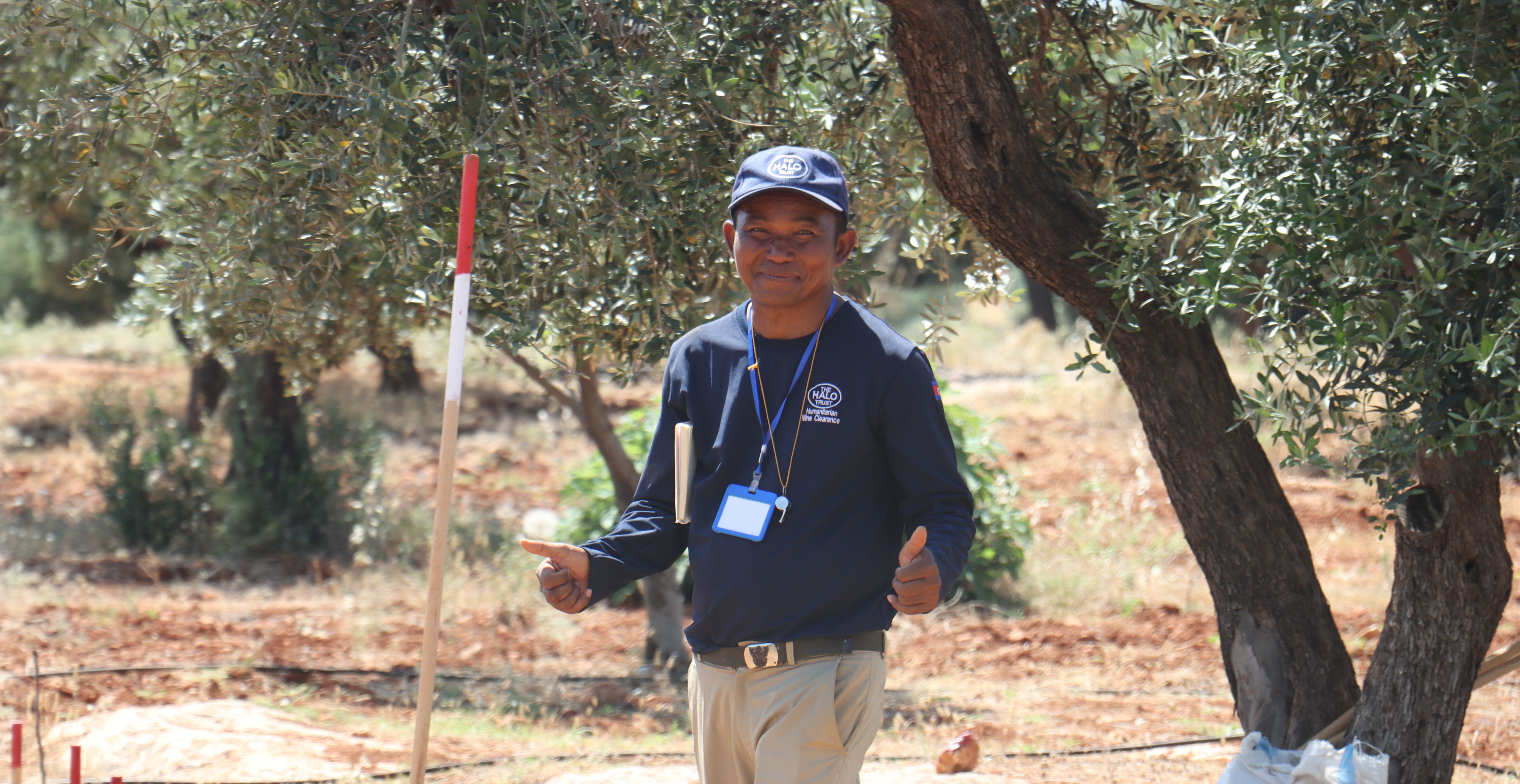 A HALO deminer smiles at the camera and gives thumbs up in a training field in Syria