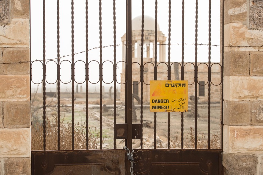 Danger of mines sign in the West Bank with a damaged church in the background