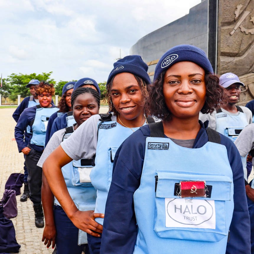 A group of female deminers stand in a line wearing HALO PPE and hats
