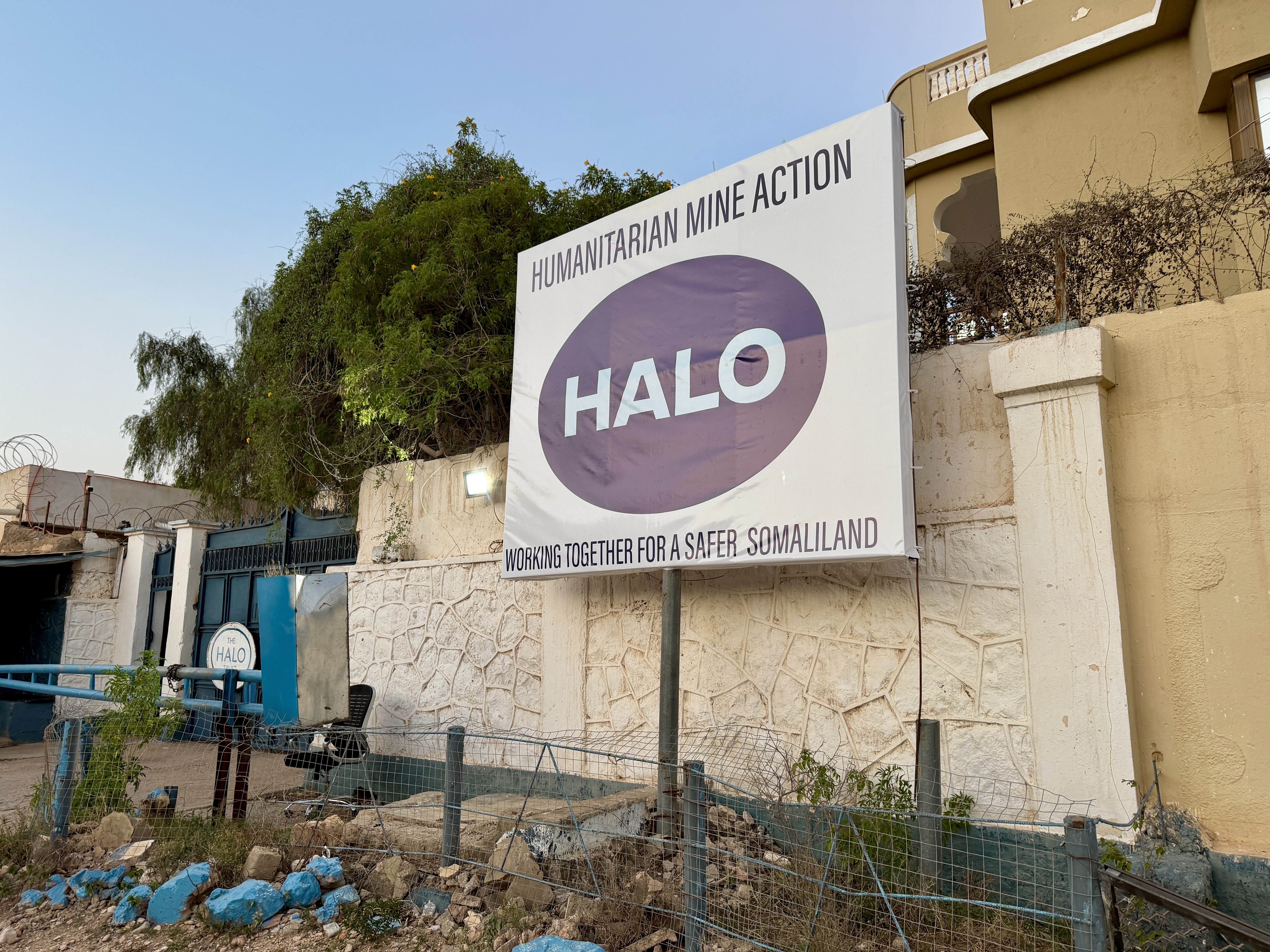 a large sign at HALO HQ in Somalia which reads "HALO: working together for a safer Somaliland"