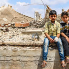 Two young boys sit on a wall in Syria