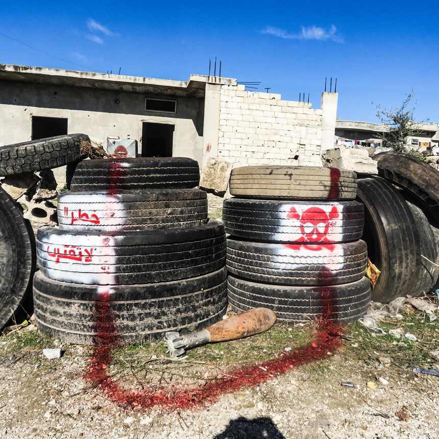An item of unexploded ordnance is cornered off by tyres and spray paint in Syria