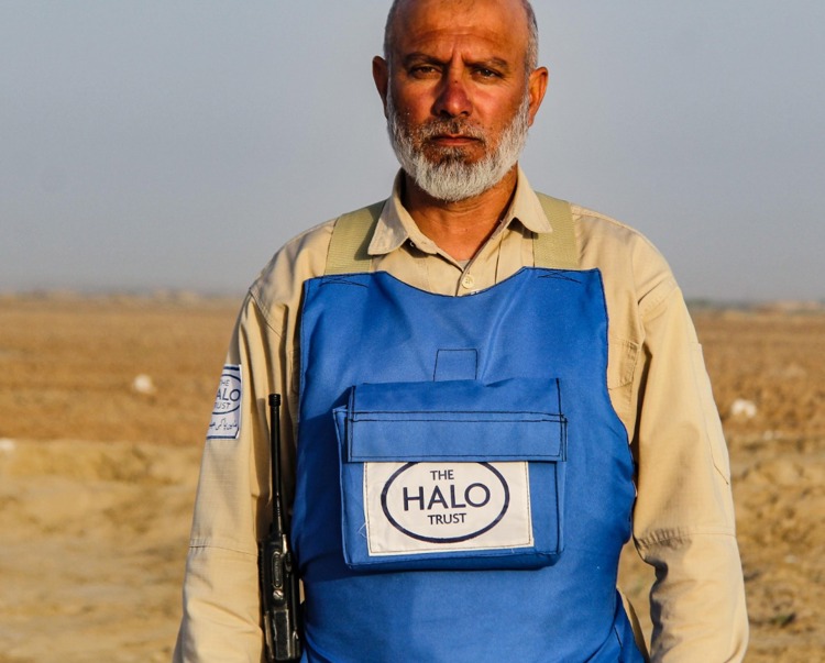 Mohammad Nazir Rahimi, stands in PPE in a minefield in Afghanistan