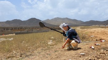 HALO Trust deminer places a marker on the ground following the positive signal from a metal detector in a minefield in Afghanistan
