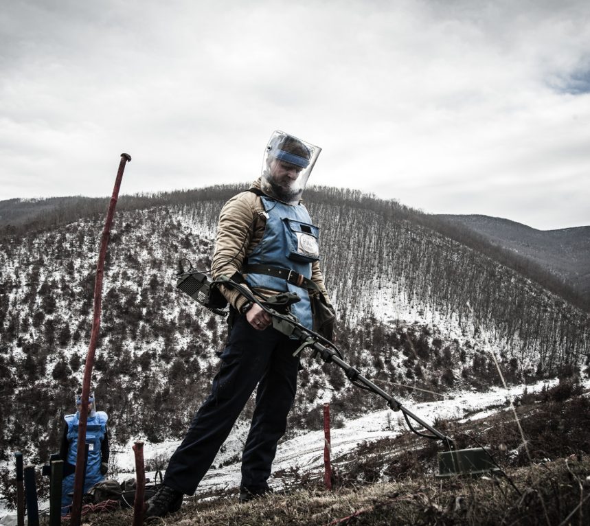 A HALO deminer in PPE scans for explosives on the hills of Kosovo