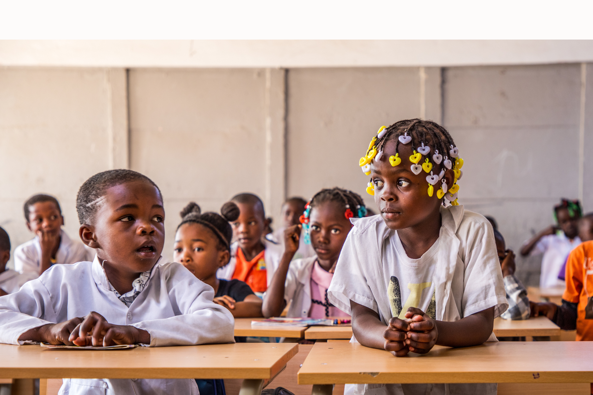 Children sit behind desks in a classroom 