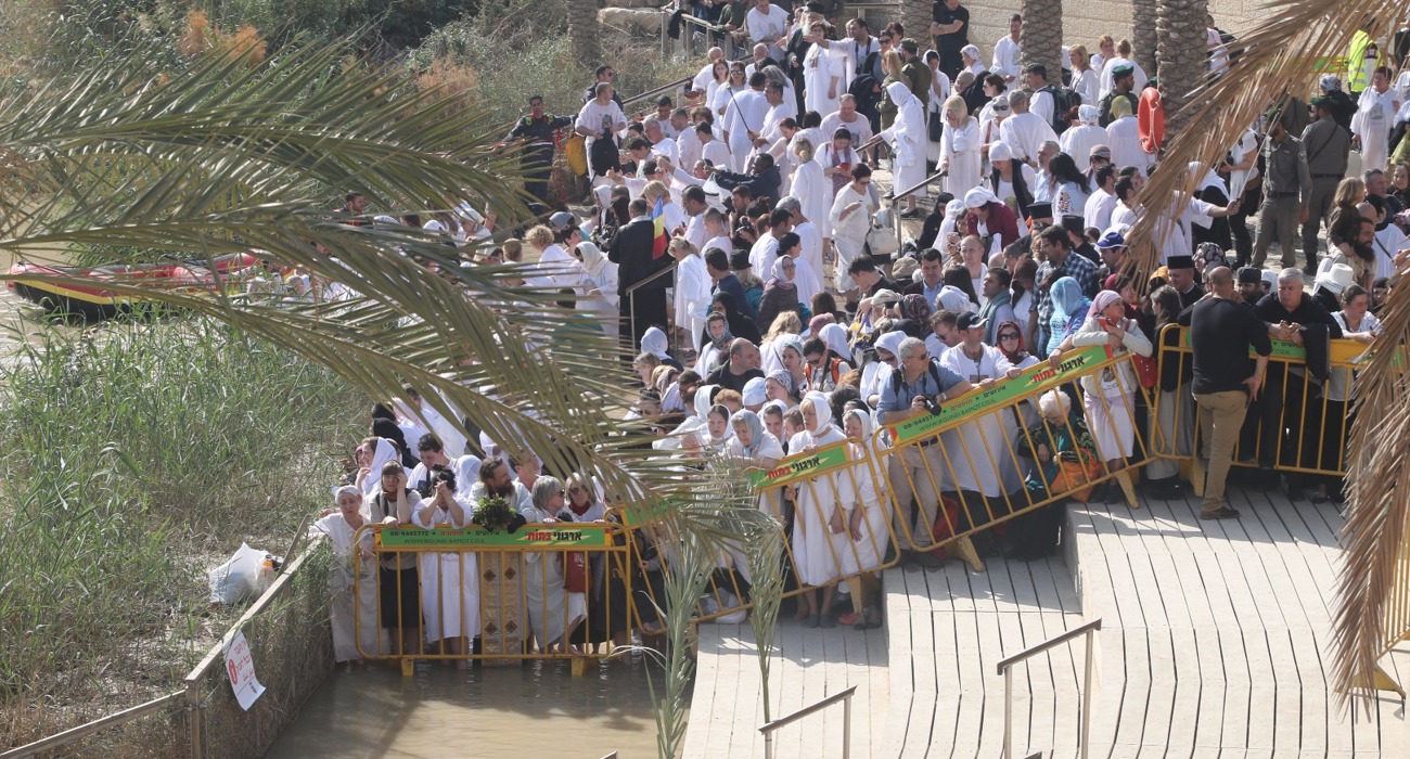 Pilgrims gathered at the Baptism Site of Christ, some wading into the Jordan River, participating in the Epiphany celebration