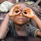 A child poses with their hands as glasses in Angola