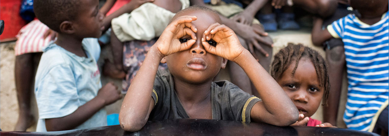 A child poses with their hands as glasses in Angola