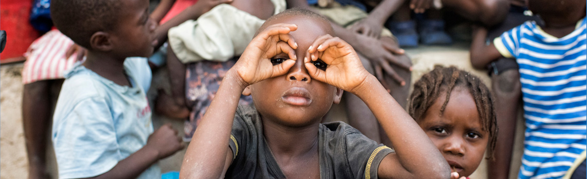 A child poses with their hands as glasses in Angola