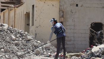 A HALO staff member wearing PPE and clearing rubble in an urban setting