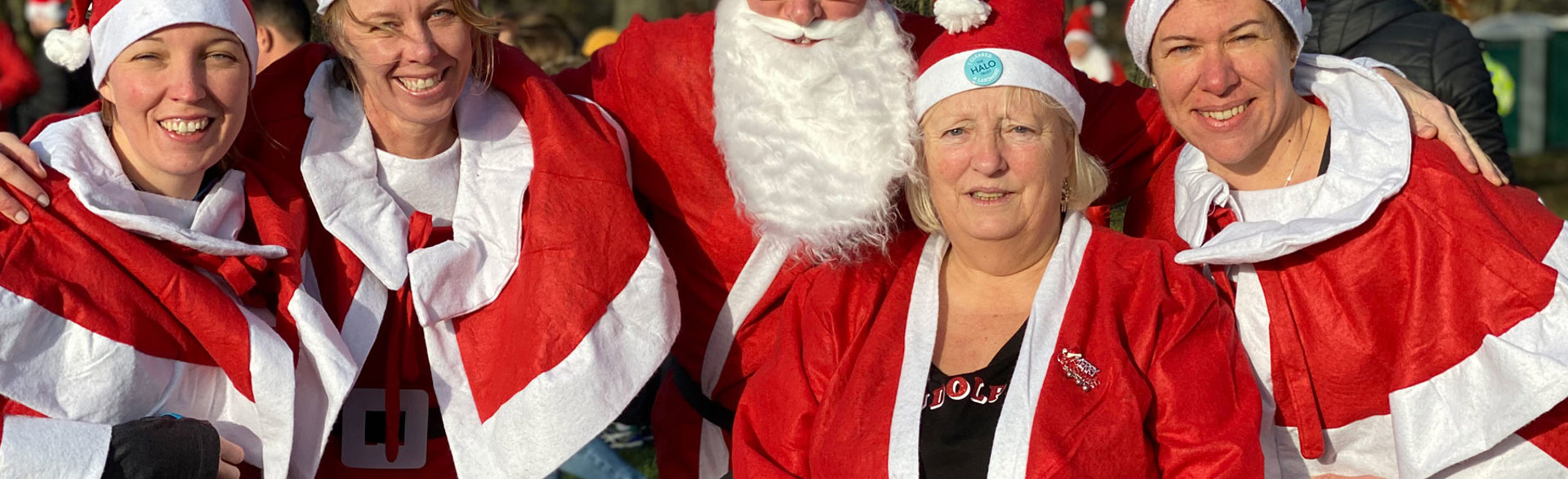 A group dressed as Santa smile at the end of a fun run