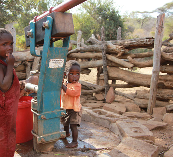 Children stand next to a borehole in Zimbabwe