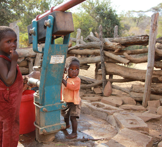 Children stand next to a borehole in Zimbabwe